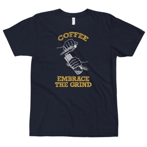 A navy blue t-shirt with a drawing of hands using a handheld coffee grinder with the words COFFEE EMBRACE THE GRIND. Designed by Kenny Velez