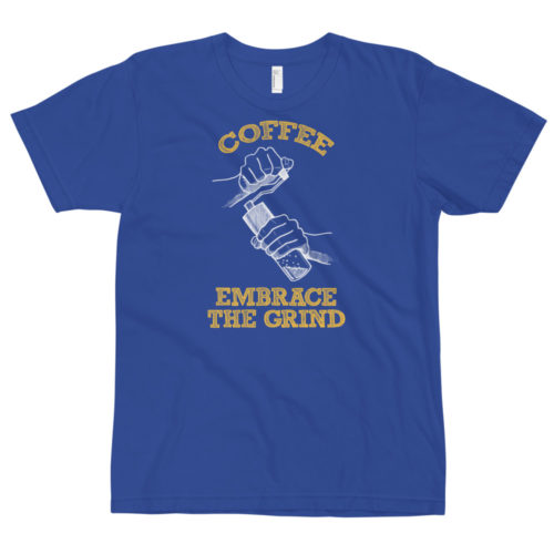 A blue t-shirt with a drawing of hands using a handheld coffee grinder with the words COFFEE EMBRACE THE GRIND. Designed by Kenny Velez