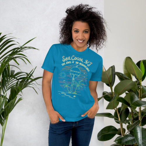 A woman wearing a teal blue t-shirt with a drawing of the water tower from Secaucus, NJ on a beach, with the words Sea Cocos, The Jewel of the Meadowlands. Designed by Kenny Velez.