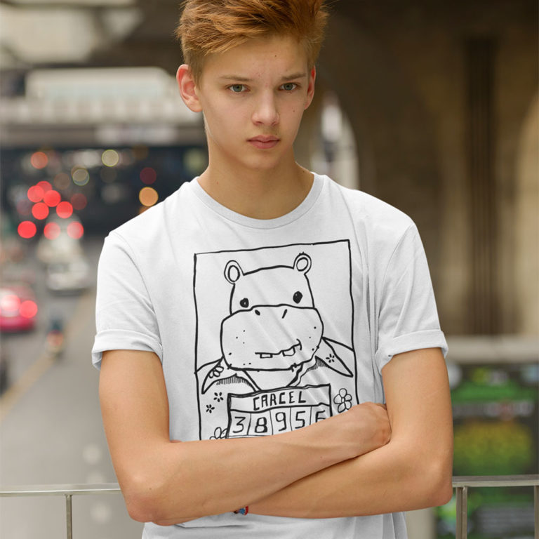 A teen kid wearing a t-shirt with a drawing of a mugshot featuring a cartoon hippo in a Hawaiian shirt in the vein of the iconic mugshot of Pablo Escobar. Designed by Kenny Velez.