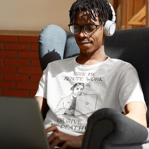 Man on a computer wearing a white t-shirt with a drawing of founding father Patrick Henry working on a laptop with the words GIVE ME REMOTE WORK OR GIVE ME DEATH! Designed by Kenny Velez