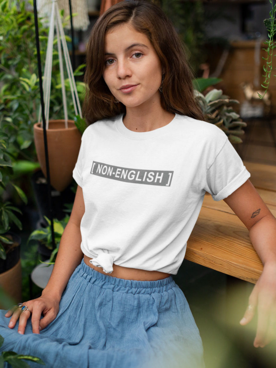 A Girl wearing a rolled-up white t-shirt with the words [NON-ENGLISH], after Bad Bunny's 2023 Grammys performance in which his Spanish was captioned as Non-Spanish.