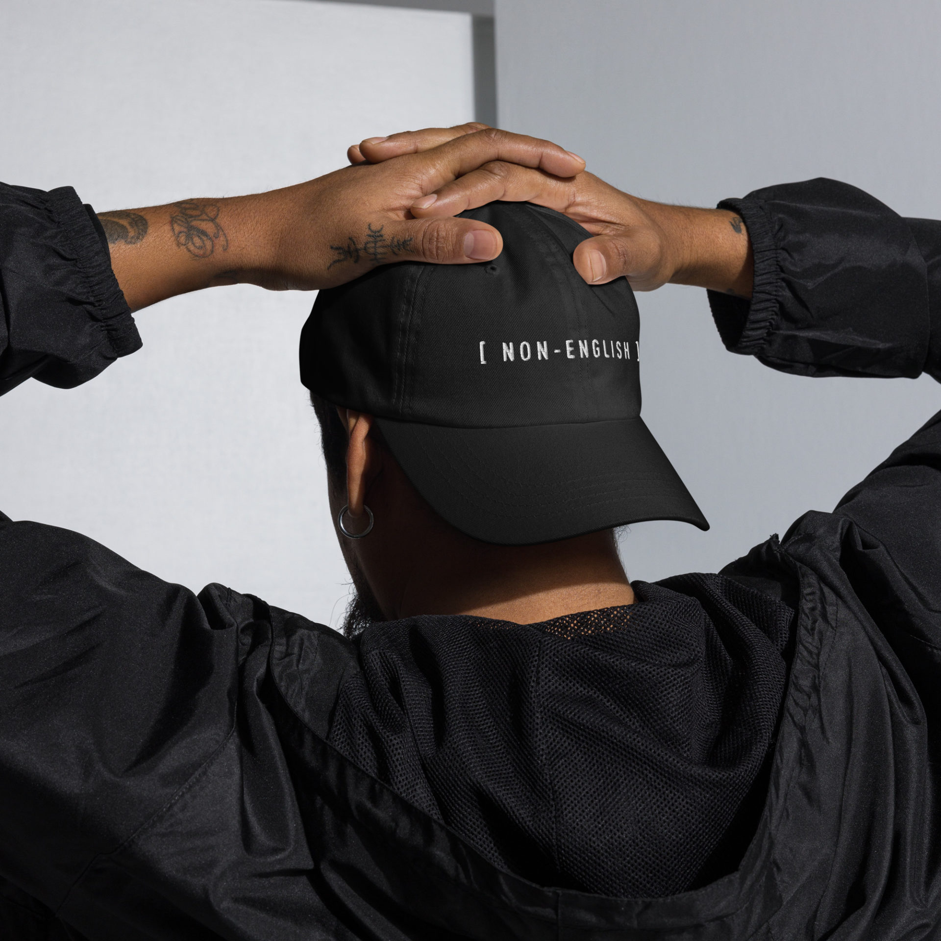 Black embroidered baseball hat with the words [NON-ENGLISH], after Bad Bunny's 2023 Grammys performance in which his Spanish was captioned as Non-Spanish.