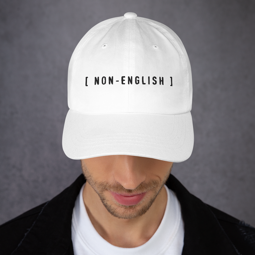 White embroidered baseball hat with the words [NON-ENGLISH], after Bad Bunny's 2023 Grammys performance in which his Spanish was captioned as Non-Spanish.