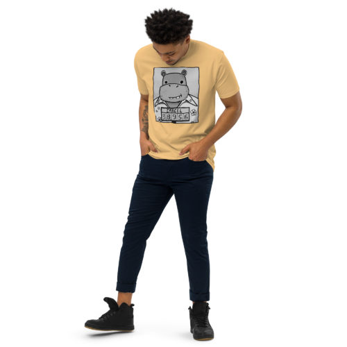 a guy wearing a yellow t-shirt with a drawing of a mugshot featuring a cartoon hippo in a Hawaiian shirt in the vein of the iconic mugshot of Pablo Escobar. Designed by Kenny Velez.