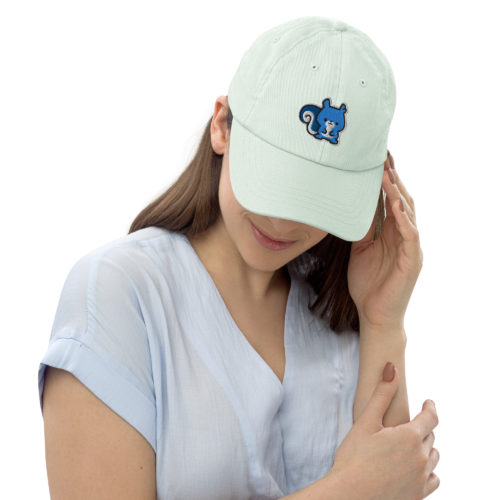 A woman wearing a mint green pastel baseball hat with a cute blue squirrel embroidery. Ma Squirrel by Kenny Velez is the brand.