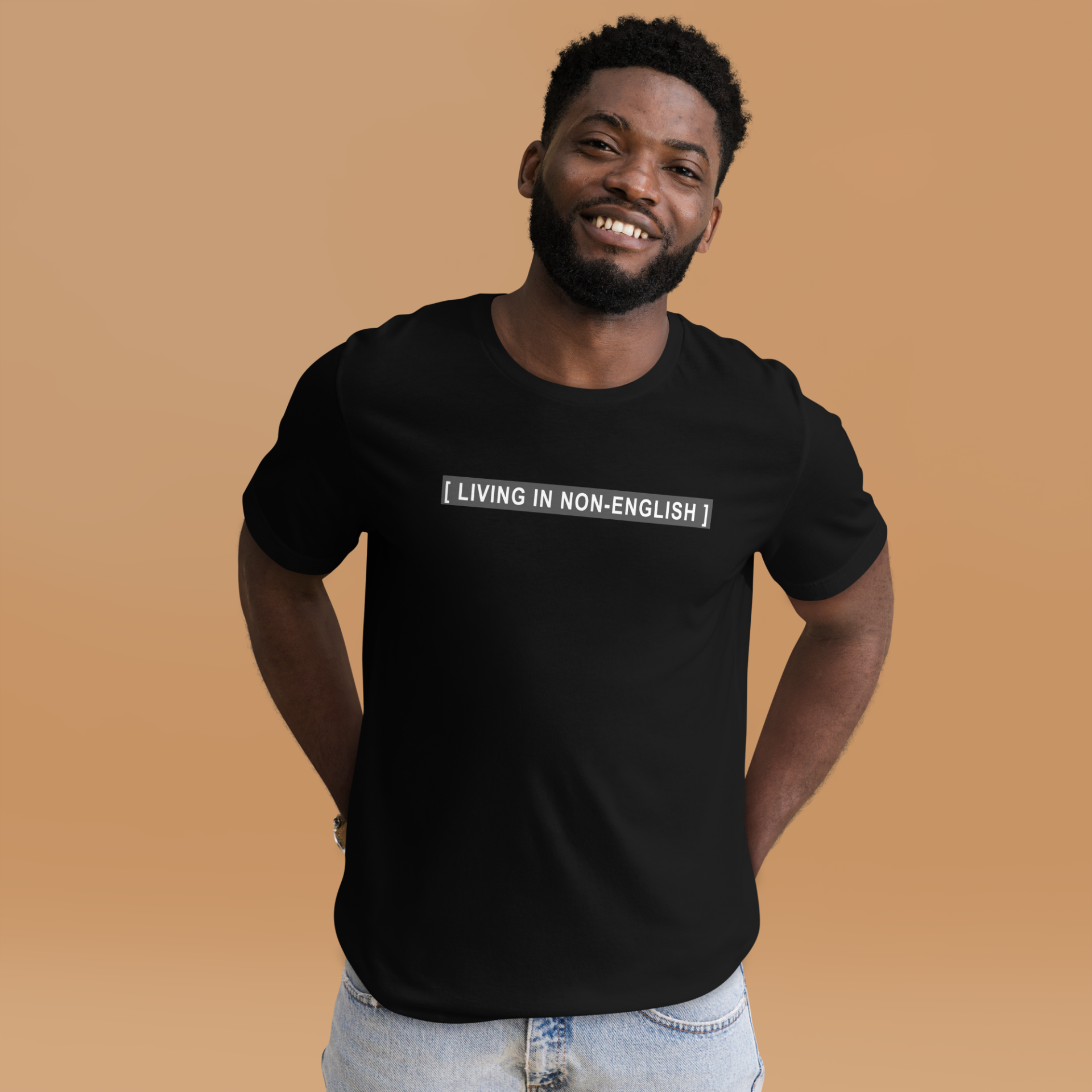 A guy wearing a black t-shirt with the words [LIVING IN NON-ENGLISH], after Bad Bunny's 2023 Grammys performance in which his Spanish was captioned as Non-Spanish.
