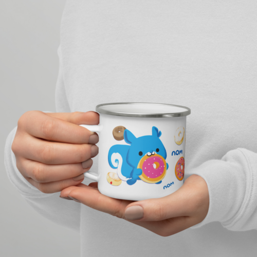 hands holding a white camper mug with a cute cartoon squirrel eating a doughnut and surrounded by donuts with the words nom