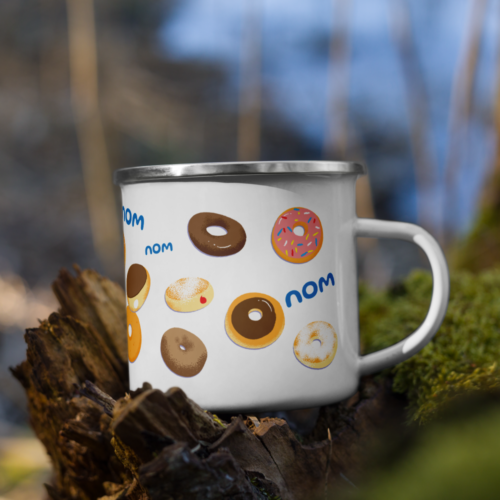 a white camper mug with a cute cartoon squirrel eating a doughnut and surrounded by donuts with the words nom