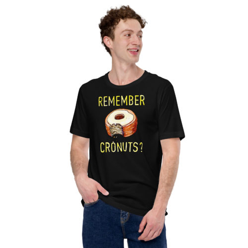 A man wearing a black t-shirt with a drawing of a bitten cronut with the words REMEMBER CRONUTS? in yellow lettering. Designed by Kenny Velez.