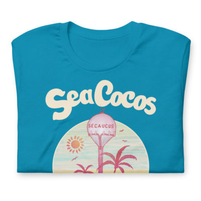 blue t-shirt with a drawing of the water tower from Secaucus, NJ on a beach, with the words Sea Cocos, La Joya de los Meadowlands. Designed by Kenny Velez.