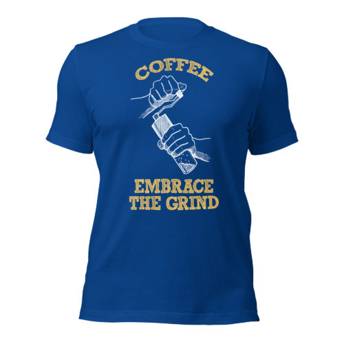 A blue t-shirt with a drawing of hands using a handheld coffee grinder with the words COFFEE EMBRACE THE GRIND in yellow lettering. Designed by Kenny Velez