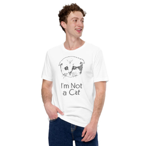 A guy wearing a white t-shirt with a drawing of a sad cat with the words I'm Not a Cat. Designed by Kenny Velez.