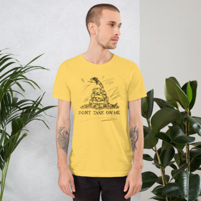 a guy wearing a yellow t-shirt with a drawing of a modified Gadsden flag but drawn in pencil with the words Don't Take on Me. A play on the a-ha - Take On Me Music Video. The snake has a mullet.