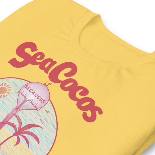yellow color t-shirt with a drawing of the water tower from Secaucus, NJ on a beach, with the words Sea Cocos, La Joya de los Meadowlands. Designed by Kenny Velez.