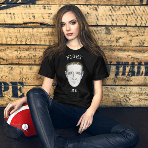 a woman wearing a black shirt with a creepy drawing of Mark Zuckerberg with the words FIGHT ME. Referencing the fight between the billionaires Elon Musk and Mark Zuckerberg